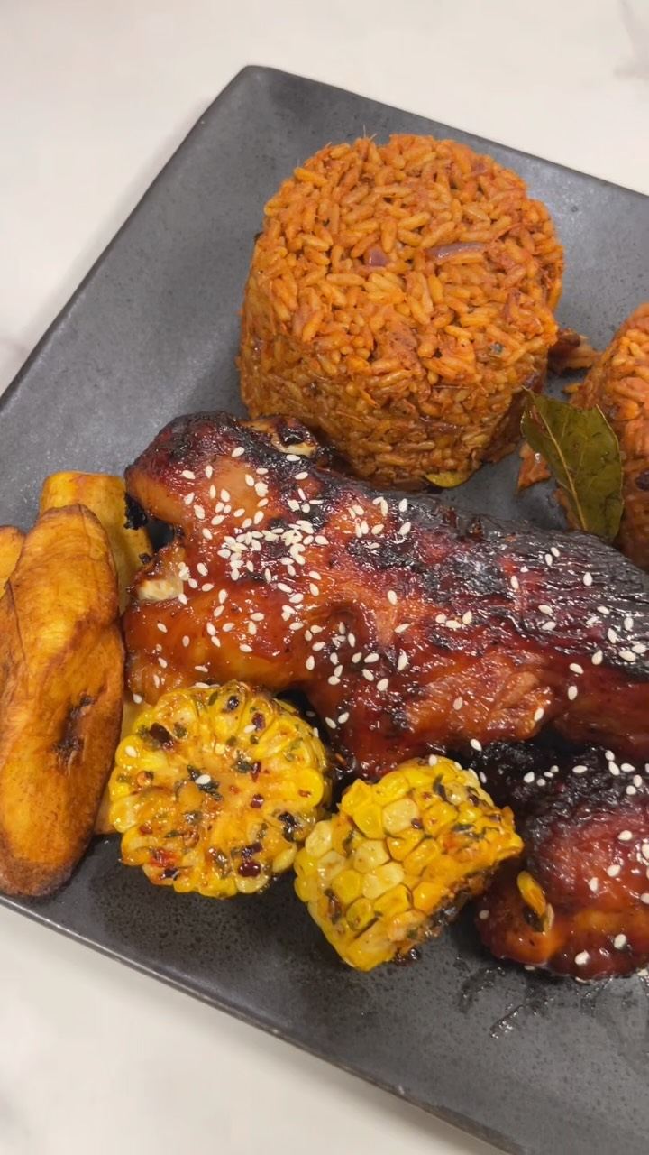 Jollof rice with glazed peppered chicken, fried plantain and corn